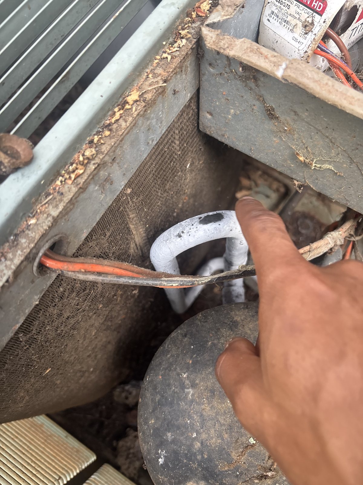 Frost-covered copper suction line at an outdoor AC unit's compressor, a sign the air conditioner is freezing up instead of cooling