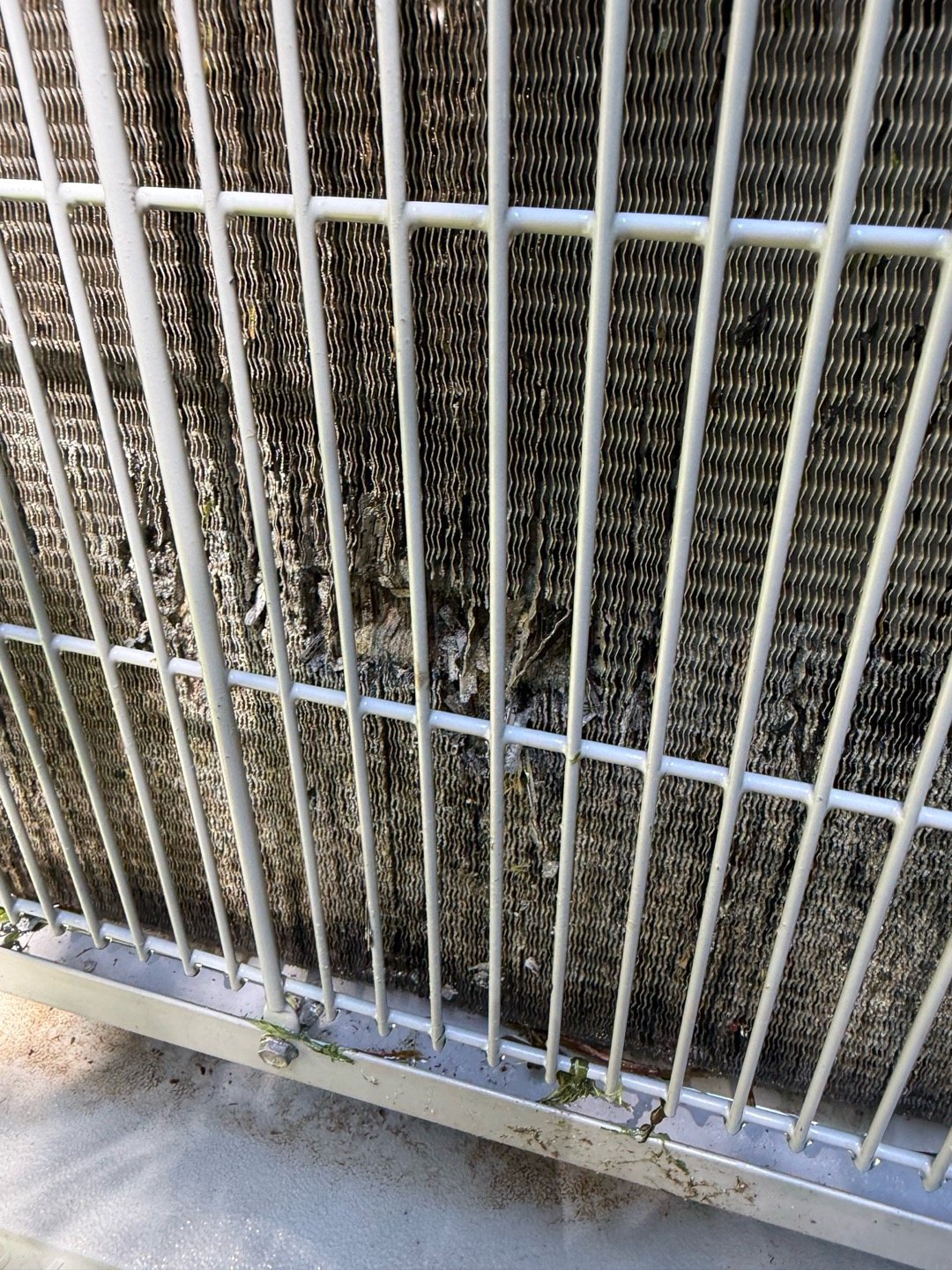 Outdoor AC condenser coil matted with dirt and debris behind its grille, keeping a Georgia air conditioner from shedding heat