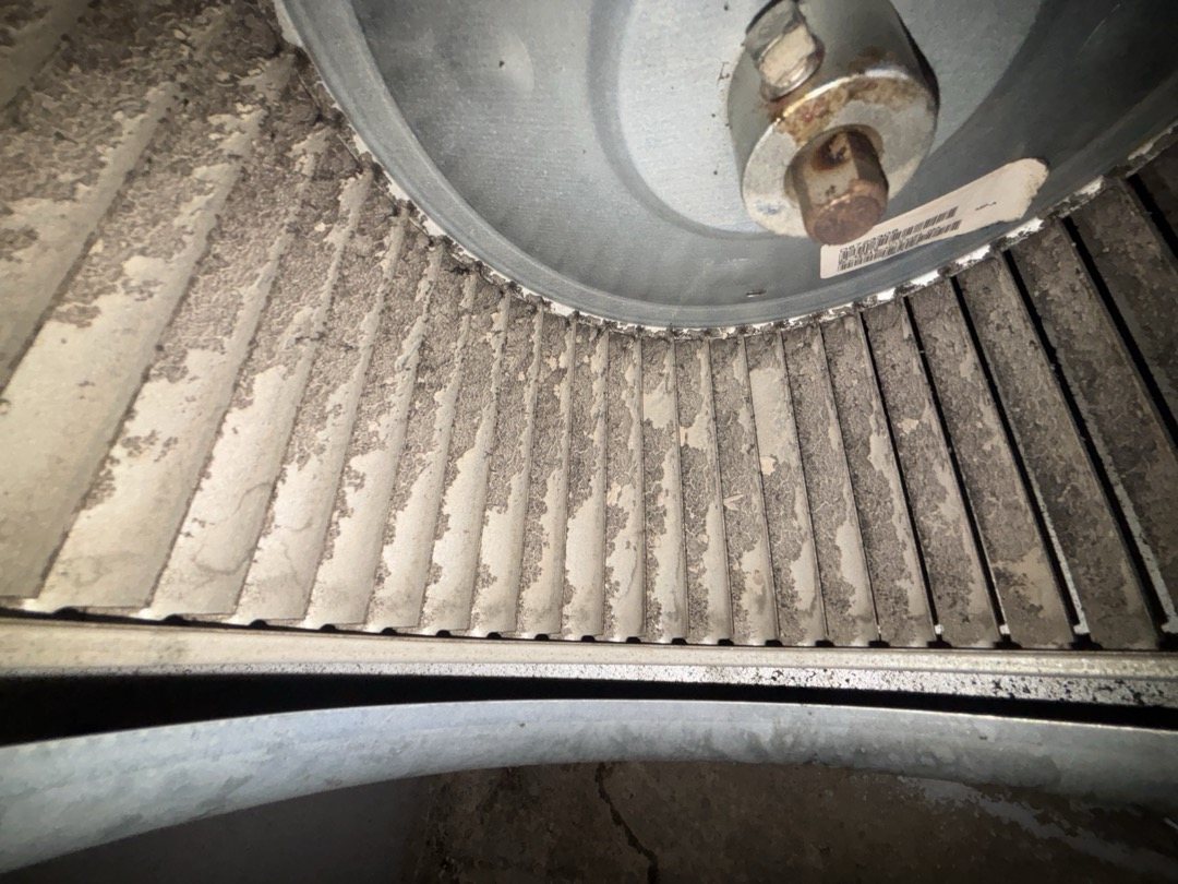 Furnace blower wheel with its fins caked in dust, which cuts airflow and can make a furnace overheat and shut off on its limit switch