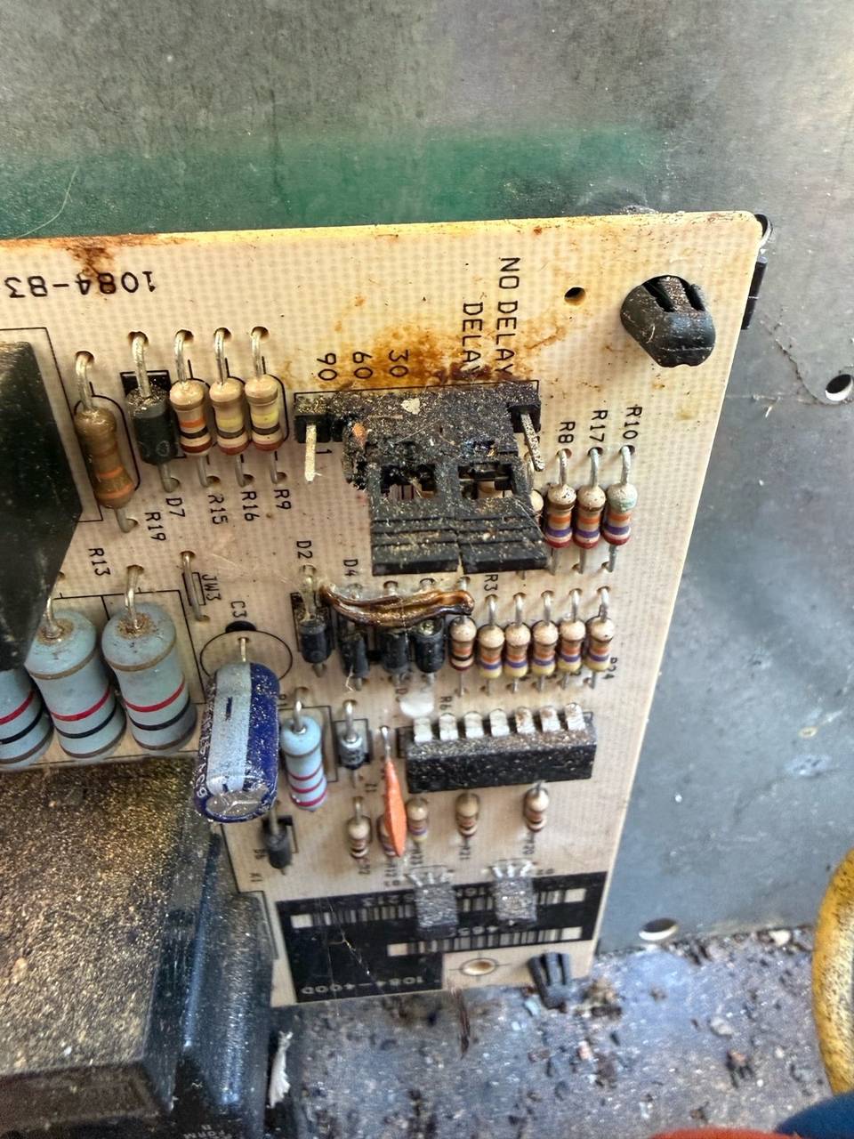 Burned and charred circuit board inside an HVAC unit, with a melted connector and heat-stained area