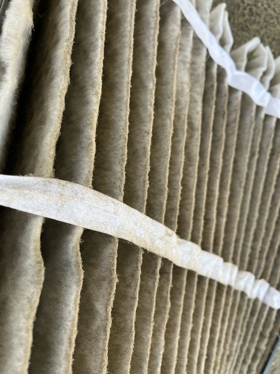 Close-up of a pleated air filter covered in a thick layer of gray dust