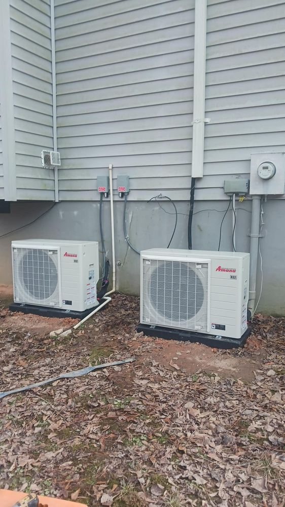 Two new Amana outdoor air conditioner units installed side by side beside a home