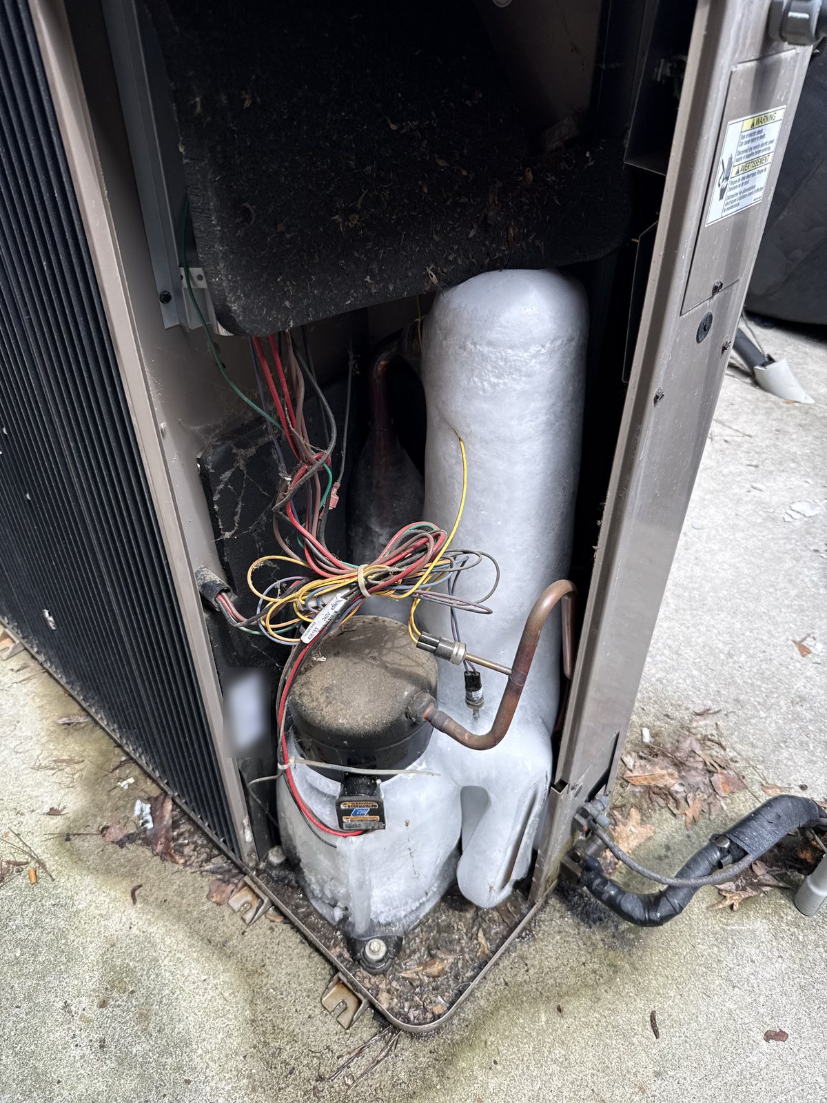 Compressor and accumulator inside a Georgia home's outdoor AC unit encased in frost and ice, a sign the air conditioner is freezing up instead of cooling
