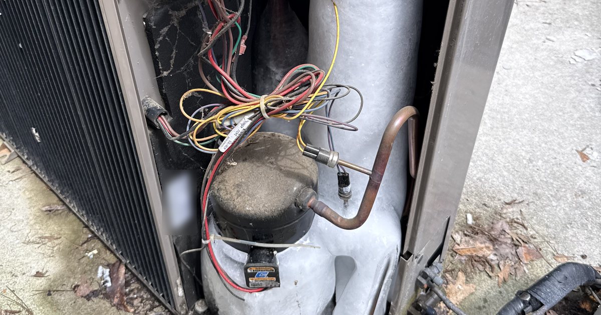Frozen AC compressor covered in ice inside an outdoor unit, a common reason an AC runs but doesn't cool