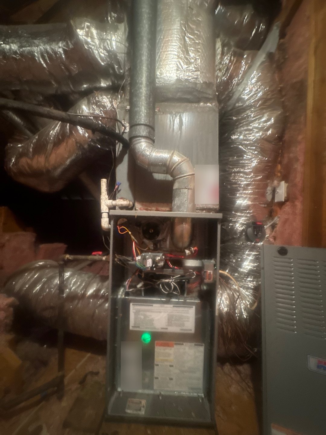 Gas furnace in a Georgia attic with its front panel off and the control board's green status light glowing, checked when a furnace is not heating