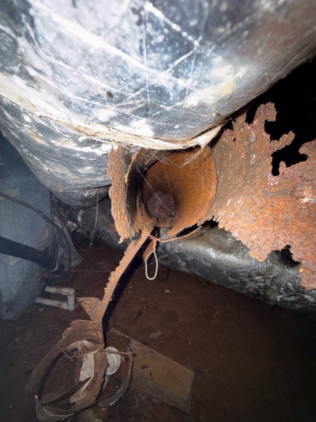 Rust that has eaten through sheet metal beneath a crawlspace heating system, a warning sign worth a professional inspection